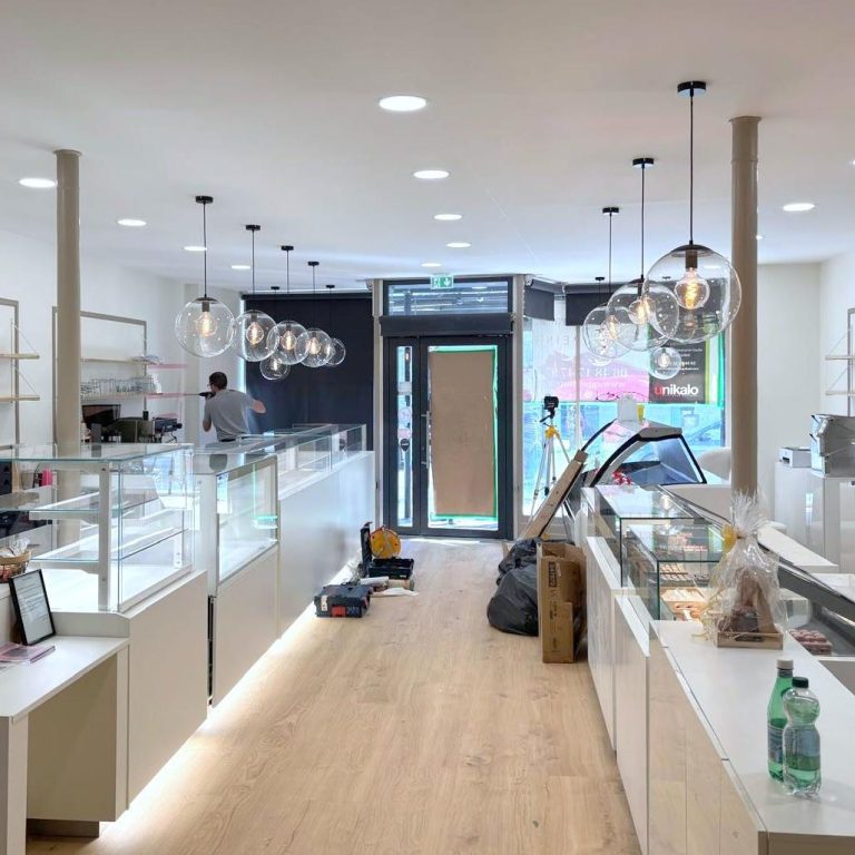 Intérieur d'une boutique moderne avec éclairage suspendu et présentoirs blancs.
