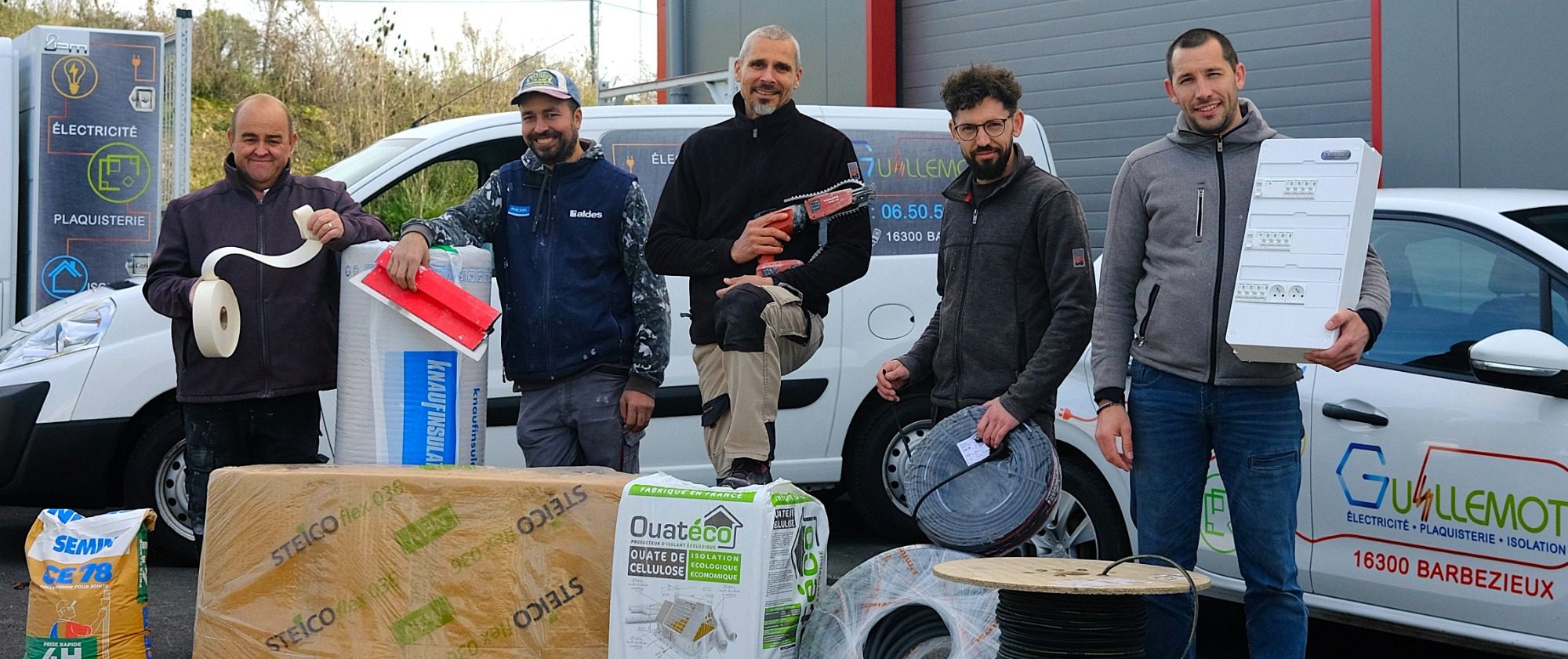 Cinq hommes posent avec des équipements et des cartons devant un véhicule utilitaire.